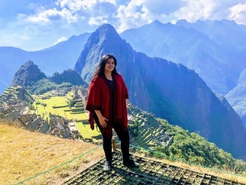 Mariel Cárdenas con un poncho rojo frente a la ciudadela de Machu Picchu, Perú