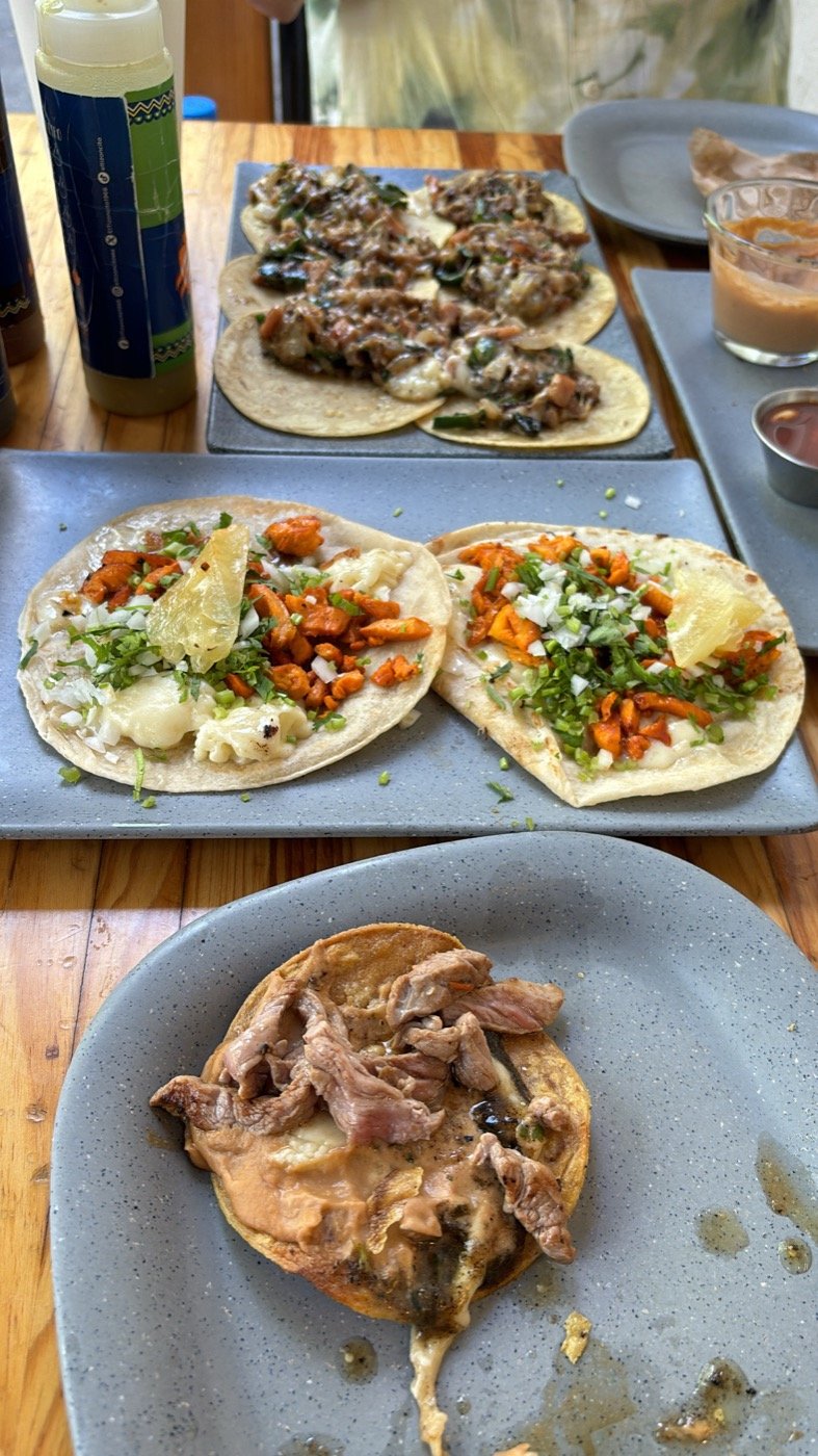 Tacos de pastor y otros platos sobre una mesa de madera en Ciudad de México