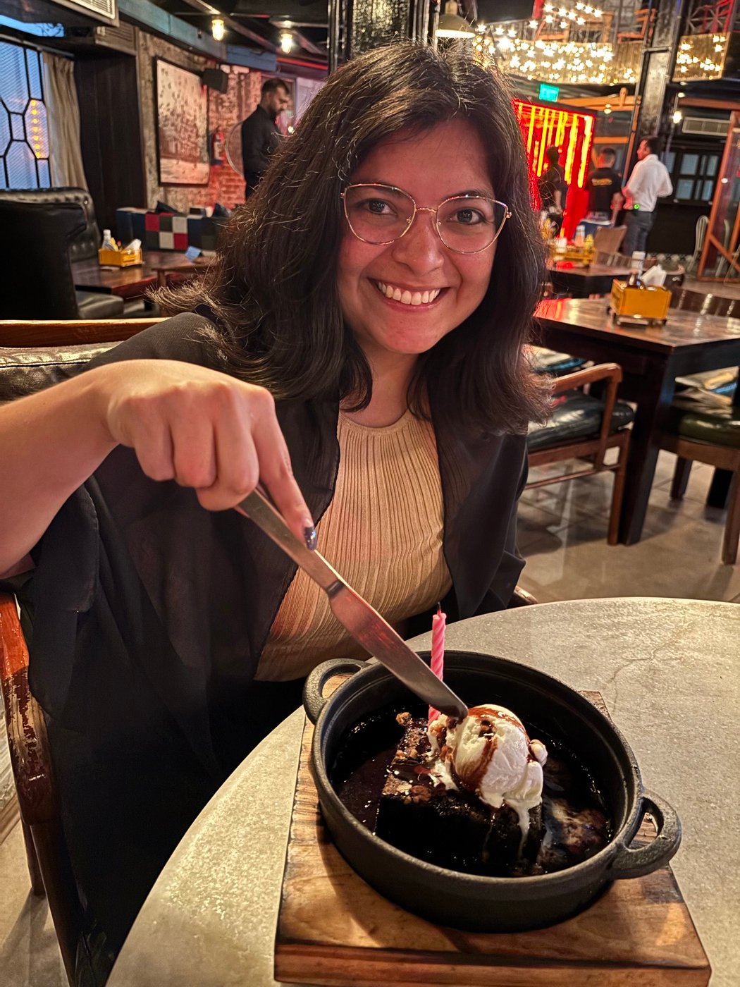 Mariel Cárdenas sonriendo con un postre de brownie con helado y una vela de cumpleaños