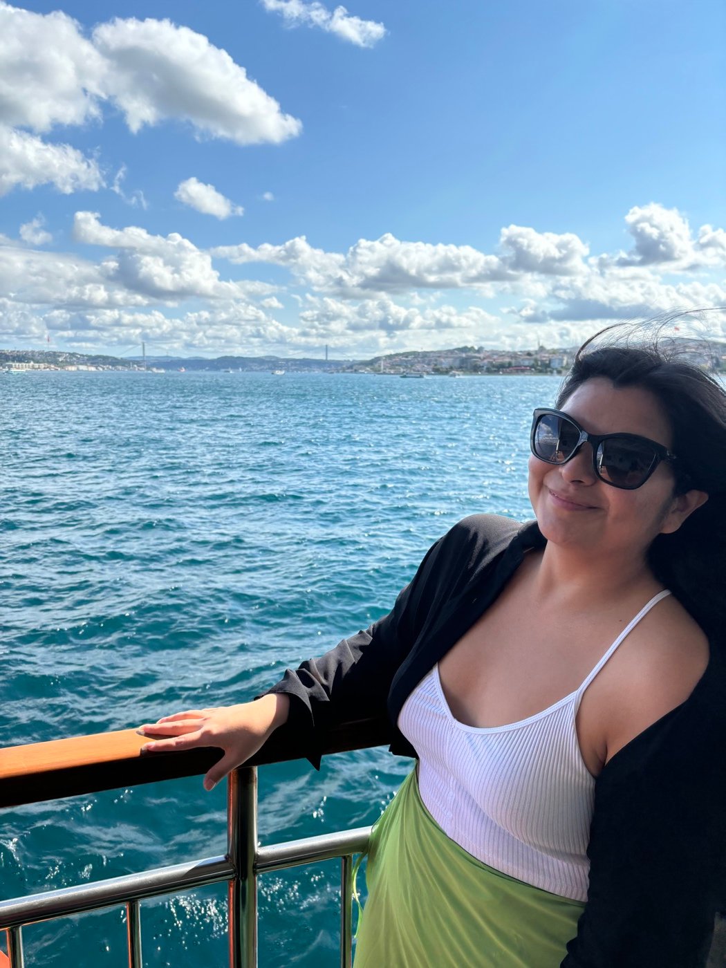 Mariel Cárdenas con lentes de sol en un barco por el Bósforo, con la costa de fondo