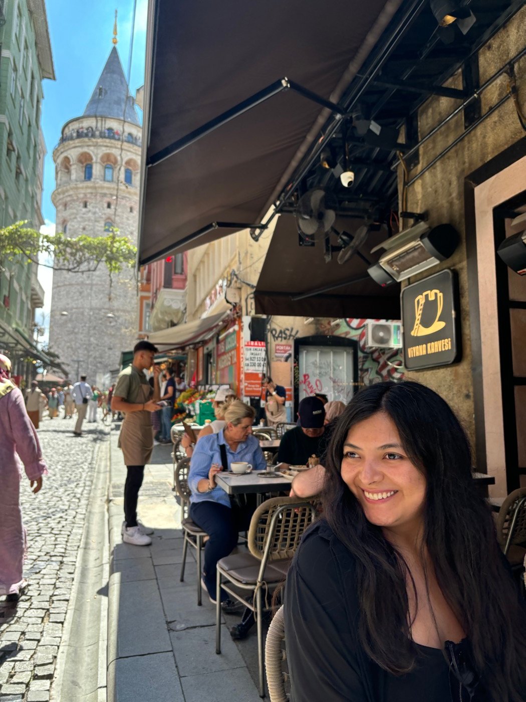 Mariel Cárdenas sonriendo en una calle empedrada con la torre de Gálata de fondo, en Estambul