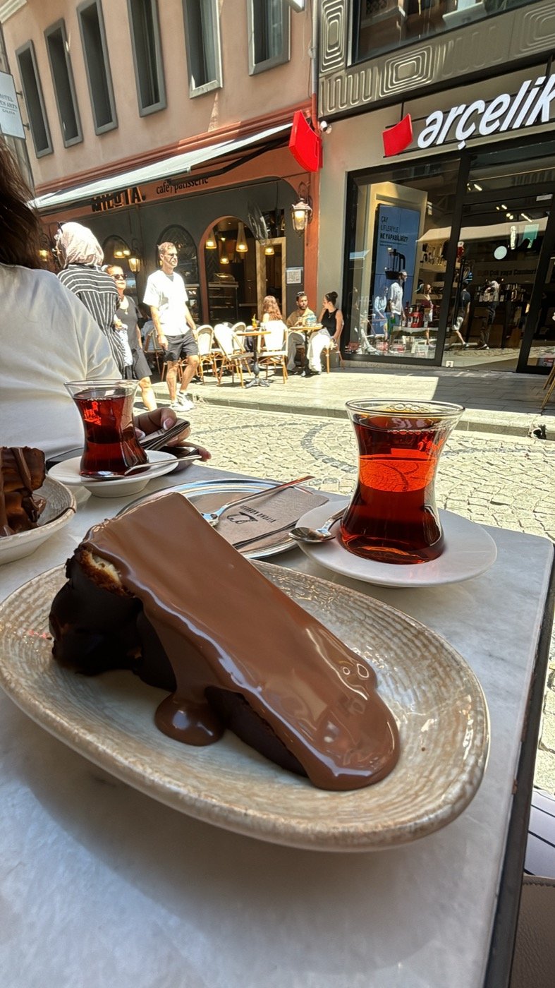 Tarta de queso San Sebastián con chocolate y un vaso de té turco en una mesa en la calle, en Estambul